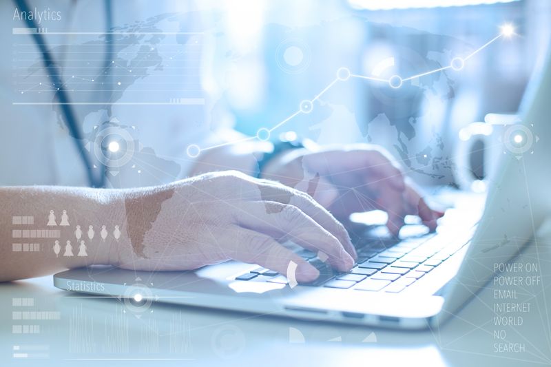 Close-up of hands typing on a laptop with a blue analytics overlay and world map in the background.
