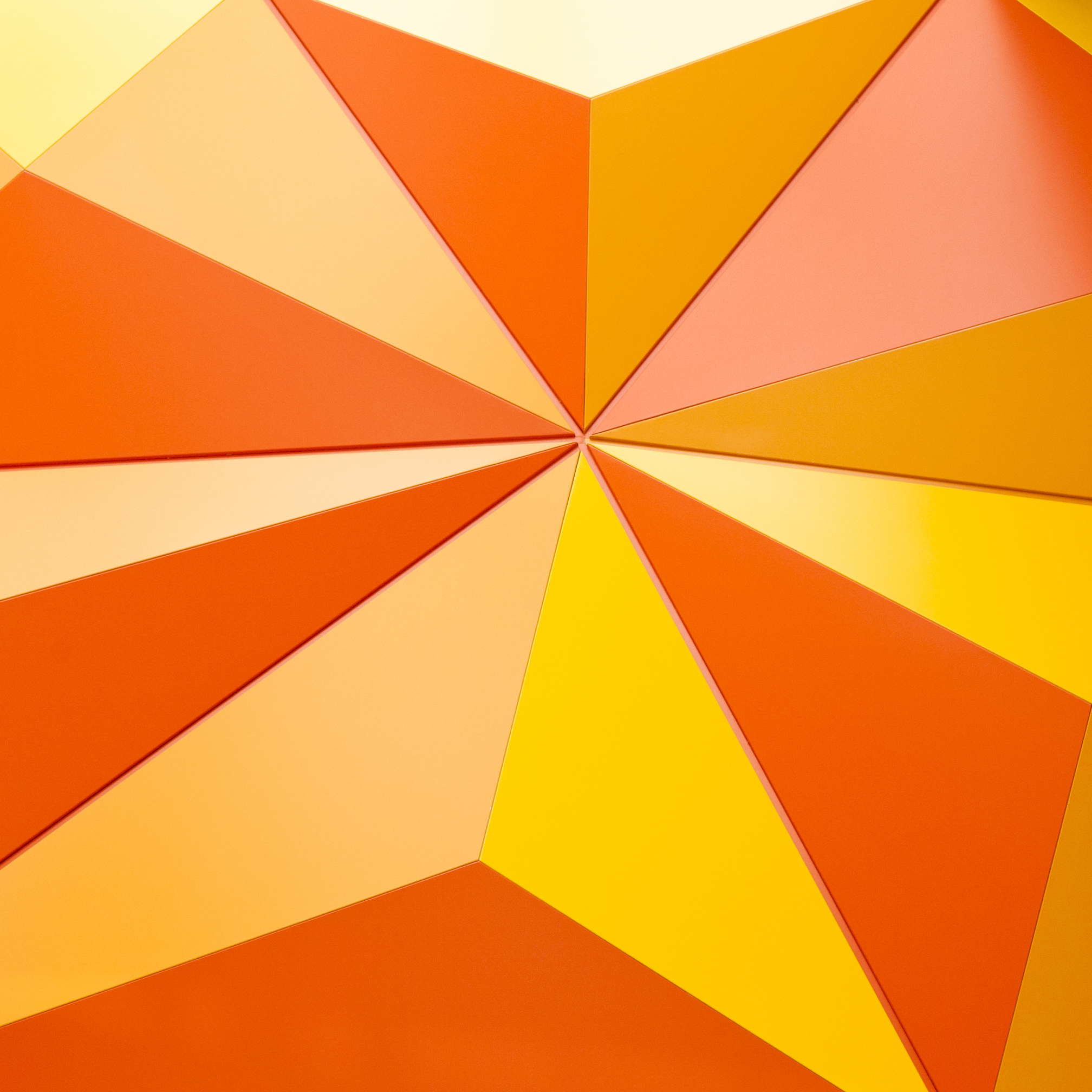 Abstract geometrical background with orange triangles - Prodify Digital Decorative abstract geometric pattern in warm orange and yellow tones with sharp triangular shapes converging at a central point.