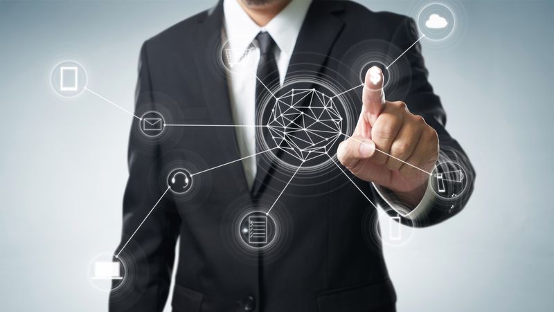 Businessman in a suit taps a holographic network hub with connected icons representing digital connectivity.